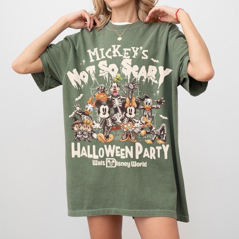 May include: Olive green t-shirt featuring a Halloween-themed graphic with Mickey Mouse and friends in skeleton costumes. The text reads "Mickey's Not So Scary Halloween Party" and "Walt Disney World."