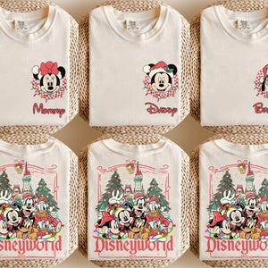 May include: Off-white t-shirts with Disney character graphics. One shirt features Minnie Mouse with the word "Mommy", another has Mickey Mouse with "Daddy", and a third has Pluto with "Brother". Other shirts display a Disneyworld graphic.