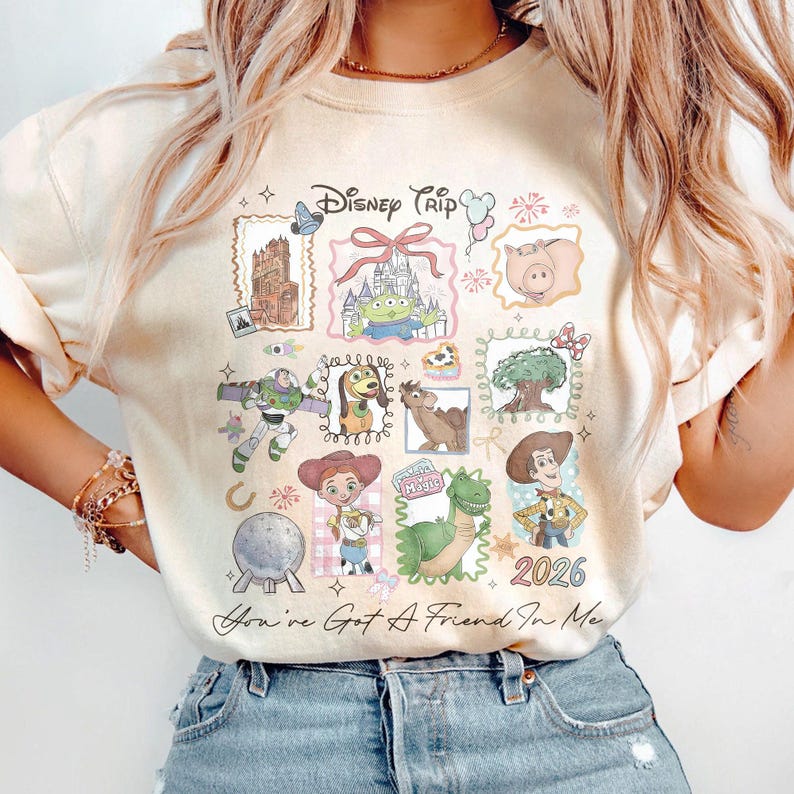 May include: Cream-colored sweatshirt featuring a Disney Trip design with various cartoon characters and landmarks. The design includes the text "Disney Trip" and "2026", along with the phrase "You've Got A Friend In Me".