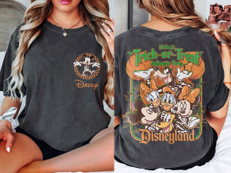 May include: A charcoal gray short-sleeve t-shirt featuring a front chest graphic of Mickey Mouse in a skeleton costume with the word Daddy. The back displays a large graphic of Disney characters in skeleton costumes with the text Mickey's Trick-or-Treat Halloween Party Disneyland.