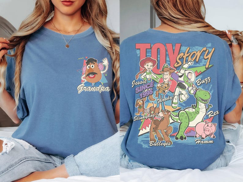 K&ouml;nnte beinhalten: Ein blaues T-Shirt mit einer Grafik von Mr. Potato Head und dem Wort "Grandpa" auf der Vorderseite. Die R&uuml;ckseite des Shirts zeigt ein "Toy Story"-Design mit Figuren wie Woody, Buzz und Rex. Der Text "Jessie Since 1995" ist ebenfalls sichtbar.