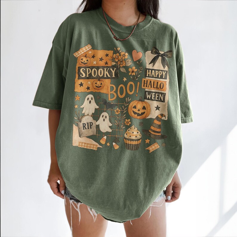 K&ouml;nnte beinhalten: Olivgr&uuml;nes T-Shirt mit einem Halloween-Motiv. Das Design zeigt K&uuml;rbisse, Geister, einen Hexenhut und die Worte "Spooky Boo! Happy Halloween". Das T-Shirt hat kurze &Auml;rmel und eine lockere Passform.