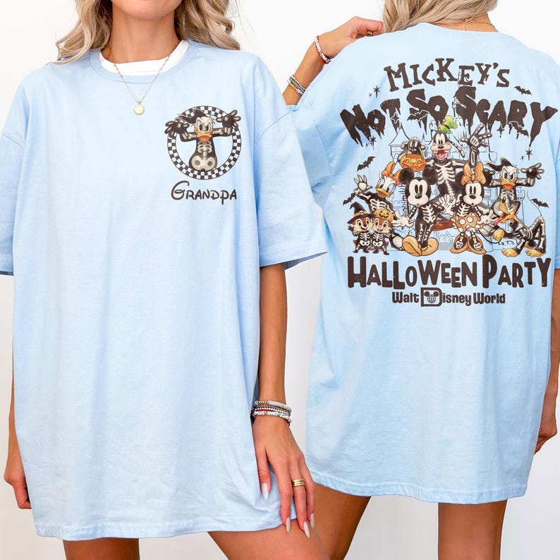 May include: Light blue t-shirts with a graphic of a cartoon character on the front and back. The front of the shirt says "Grandpa" with a cartoon character in a checkered circle. The back of the shirt says "Mickey's Not So Scary Halloween Party" with Disney characters.