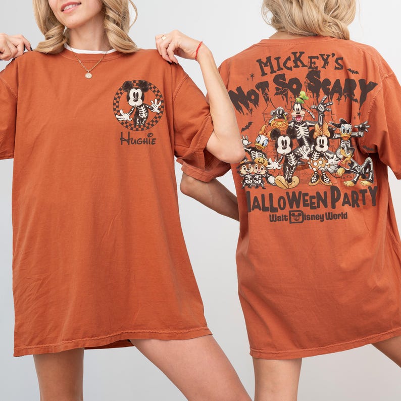 May include: Burnt orange t-shirt featuring a Halloween-themed Mickey Mouse skeleton graphic on the front and back. The front has the name "Hughie" and the back says "Mickey's Not So Scary Halloween Party" with Disney characters.