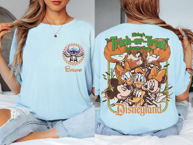 May include: A light blue t-shirt featuring a small circular graphic on the front with a character in a skeleton costume and the name Bruno. The back displays a large graphic of various cartoon characters in skeleton costumes with the text Mickey's Trick-or-Treat Halloween Party Disneyland.