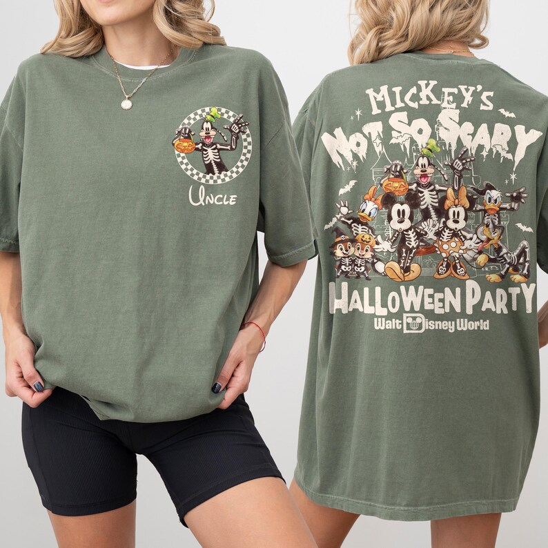 May include: Olive green t-shirt featuring a Halloween-themed graphic. The front displays a skeleton Goofy with a pumpkin and the word "Uncle." The back showcases Mickey Mouse and friends as skeletons, with the text "Mickey's Not So Scary Halloween Party" and "Walt Disney World."