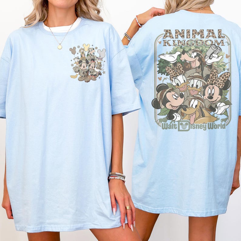 Puede incluir: Camiseta azul claro con un dise&ntilde;o de Animal Kingdom de Disney. La parte delantera tiene un peque&ntilde;o gr&aacute;fico de Mickey Mouse y Minnie Mouse. La parte trasera muestra un dise&ntilde;o m&aacute;s grande con el texto "ANIMAL KINGDOM" y "Walt Disney World".