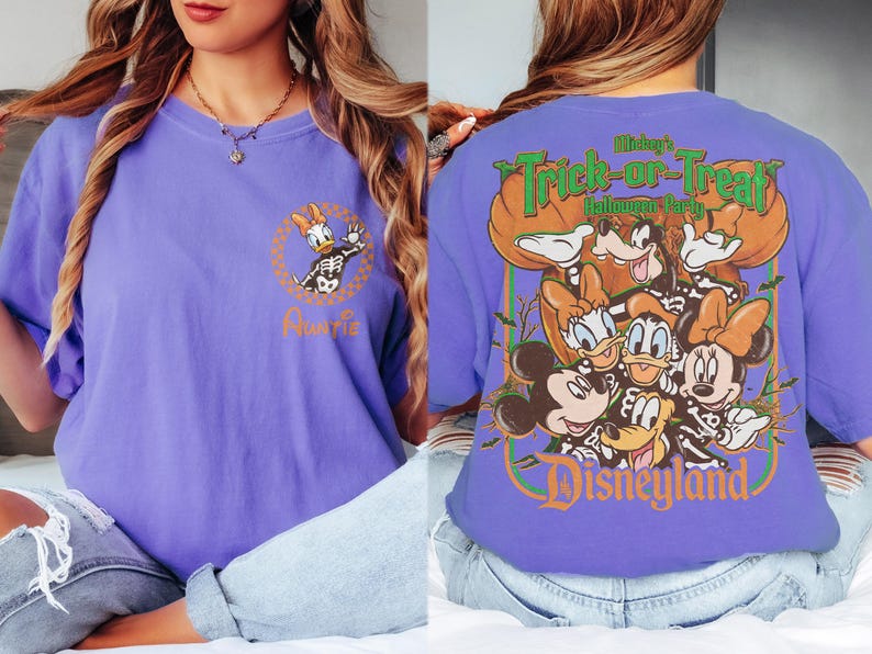 May include: A purple t-shirt featuring a front graphic of Daisy Duck in a skeleton costume inside a checkered circle with the word Auntie. The back displays Mickey, Minnie, Donald, Daisy, and Goofy in skeleton costumes with the text Mickey's Trick-or-Treat Halloween Party Disneyland.
