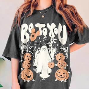 May include: Dark grey t-shirt with a Halloween graphic. The design includes the text "Be to You", a ghost holding a pumpkin bucket, pumpkins, and a castle silhouette. A balloon is also included in the design.