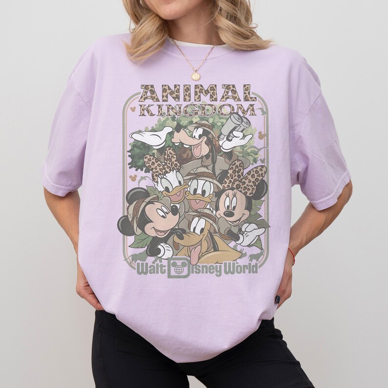 May include: A light purple t-shirt featuring a graphic of Disney characters, including Mickey and Minnie Mouse, Donald and Daisy Duck, and Goofy. The text "ANIMAL KINGDOM" and "Walt Disney World" are also displayed.