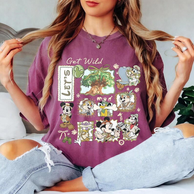 May include: A purple t-shirt with a graphic design featuring cartoon characters and the text "Get Wild" and "Let's". The design includes images of Mickey Mouse, Chip and Dale, and other characters in safari-themed outfits.