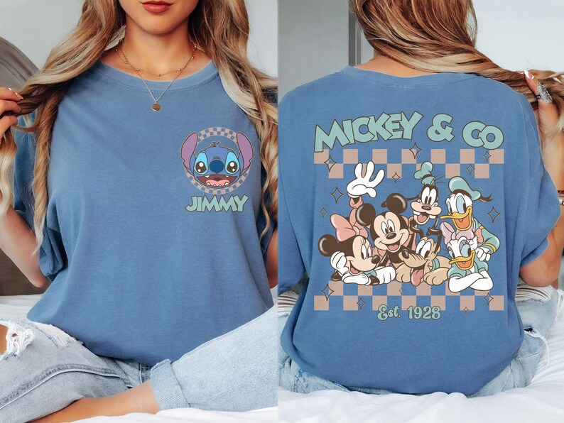 K&ouml;nnte beinhalten: Blaues T-Shirt mit Stitch und dem Namen "JIMMY" auf der Vorderseite. Auf der R&uuml;ckseite steht "MICKEY & CO" mit Disney-Figuren und "Est 1928" in einem Schachbrettmuster. Bequemer, l&auml;ssiger Stil.