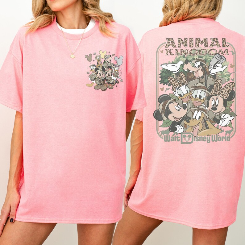 Puede incluir: Camiseta rosa claro con un dise&ntilde;o de Disney. La parte delantera tiene un peque&ntilde;o dise&ntilde;o con Mickey y Minnie Mouse, y la parte trasera muestra "ANIMAL KINGDOM" y "Walt Disney World". Los personajes visten trajes de safari.