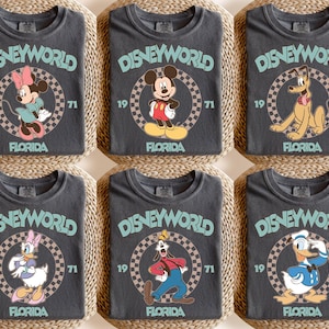 May include: Six charcoal gray t-shirts featuring Disney characters. Each shirt has the text "DISNEYWORLD FLORIDA 1971" in a circular design. Characters include Minnie Mouse, Mickey Mouse, Pluto, Daisy Duck, Goofy, and Donald Duck.