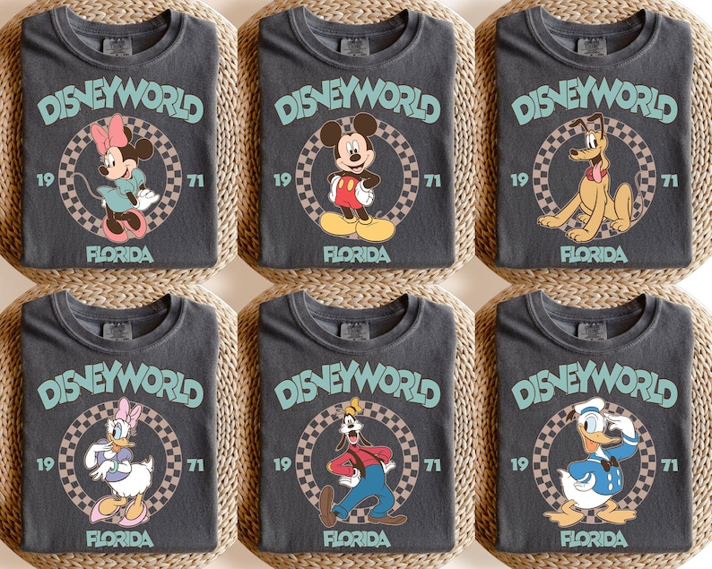 May include: Six charcoal gray t-shirts featuring Disney characters. Each shirt has the text "DISNEYWORLD FLORIDA 1971" in a circular design. Characters include Minnie Mouse, Mickey Mouse, Pluto, Daisy Duck, Goofy, and Donald Duck.