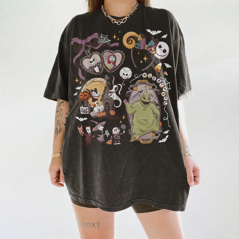 May include: Dark grey t-shirt with a colourful graphic from "The Nightmare Before Christmas." The design includes Jack Skellington, Sally, Oogie Boogie, and other characters. The shirt has a vintage, worn appearance.