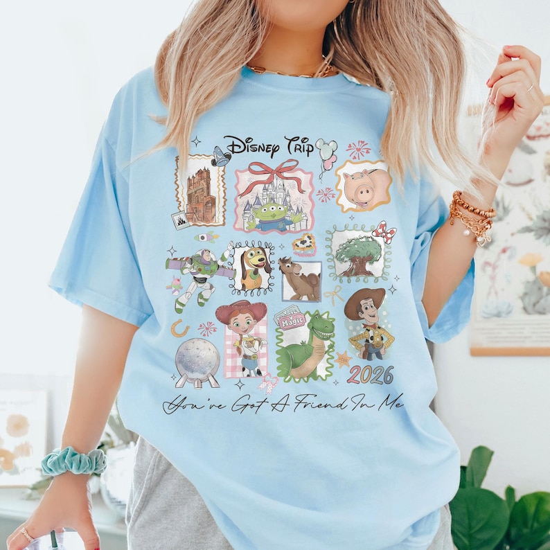 May include: Light blue t-shirt featuring a Disney Trip design with various character illustrations and the text "You've Got A Friend In Me" and "2026". The shirt has a crew neck and short sleeves.