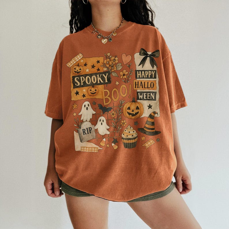 K&ouml;nnte beinhalten: Orangefarbenes T-Shirt mit einem Halloween-Motiv. Das Design umfasst K&uuml;rbisse, Geister, einen Hexenhut und die Worte "Spooky Boo! Happy Halloween". Das kurz&auml;rmelige T-Shirt hat eine lockere Passform, ideal f&uuml;r den Herbst.