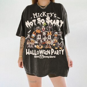 May include: Black t-shirt featuring a graphic of Disney characters in skeleton form, with the text "Mickey's Not So Scary Halloween Party" and "Walt Disney World". The design includes Mickey Mouse, Minnie Mouse, Donald Duck, and other characters.