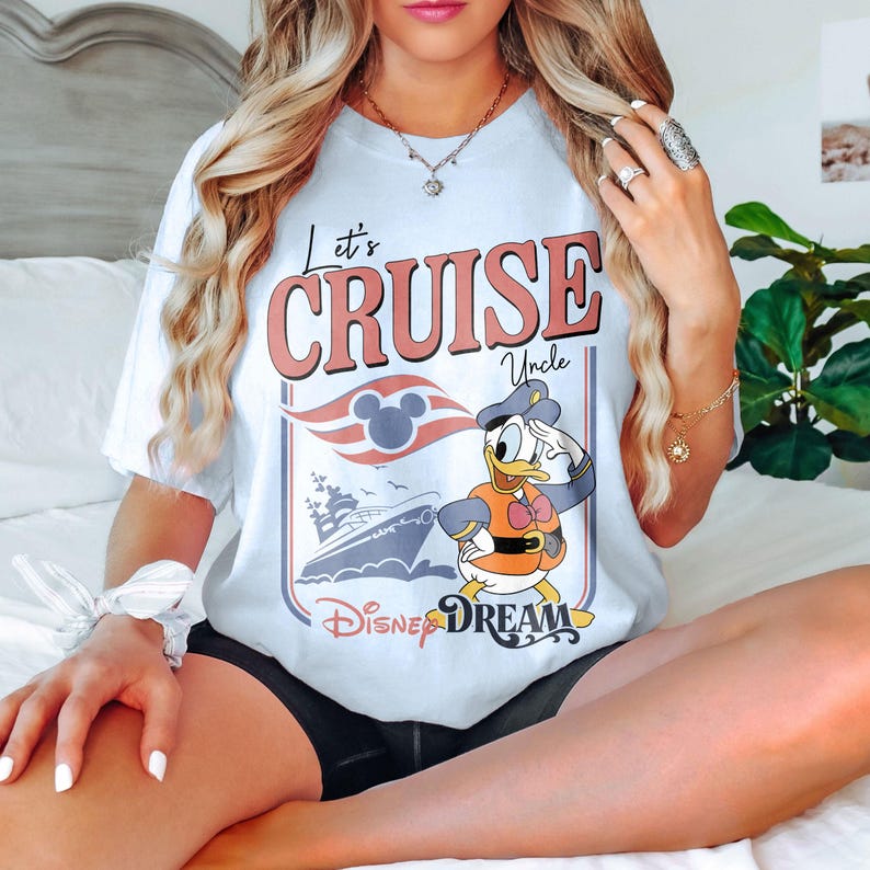 May include: White t-shirt with the text "Let's Cruise Uncle" in red and pink. Features a graphic of Donald Duck in a sailor outfit, a cruise ship, and the words "Disney Dream".