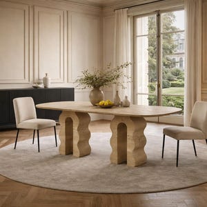 Puede incluir: Un comedor con una mesa ovalada de color claro con soportes arqueados. Dos sillas crema con patas negras se sitúan a ambos lados de la mesa, sobre una alfombra redonda gris claro. Un aparador negro y una lámpara de pie completan la escena.