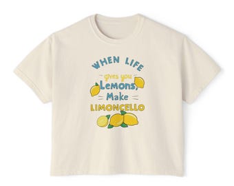 May include: A cream-colored t-shirt with a graphic print that says "When life gives you lemons, make limoncello". The graphic includes lemons and a green leaf.