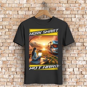 Könnte beinhalten: Schwarzes T-Shirt mit einem Grafikdesign, das eine Frau zeigt, die an einem Laptop an einem See bei Sonnenuntergang arbeitet, mit einem Wohnmobil im Hintergrund. Der Text lautet "WORK SMART NOT HARD" in Gelb.