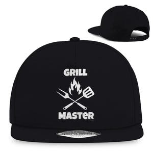 Könnte beinhalten: Schwarze und weiße Baseballkappe mit flachem Schirm mit dem Text "Grill Master" und einer Grafik mit einer Flamme und gekreuzten Grillwerkzeugen.