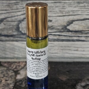 May include: A blue and gold glass roller bottle with a label that reads "Dent's Witchery Fuck Off, Headache! Bedtime". The label also includes instructions for use and a list of ingredients, including Grapeseed Oil, Lavender EO, Bergamot EO, Frankincense EO. The bottle contains 10 ml of liquid and is made in Rochdale, TX.