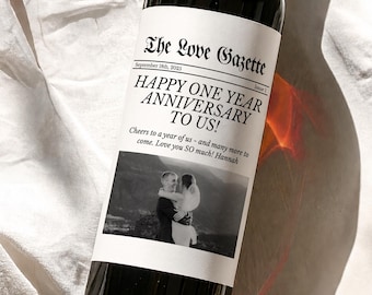 Peut inclure: Une bouteille de vin en verre foncé avec une étiquette blanche personnalisée intitulée The Love Gazette. L'étiquette porte le texte September 18th, 2025, Issue 1, HAPPY ONE YEAR ANNIVERSARY TO US! et une photo en noir et blanc d'un couple.