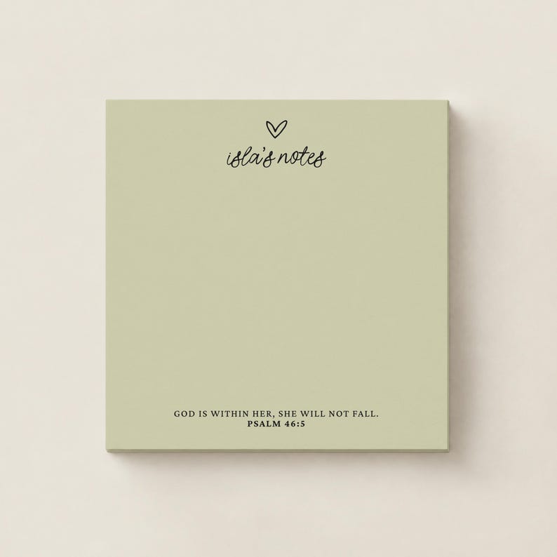May include: A square sage green notepad featuring a small black heart icon above the text "isla's notes" in a cursive script. At the bottom, the text "GOD IS WITHIN HER, SHE WILL NOT FALL. PSALM 46:5" is printed in a clean black serif font.