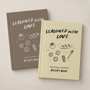 May include: Two hardcover recipe books with a matte finish. The brown book features white text reading SEASONED WITH LOVE and FINN & JESSICA'S RECIPE BOOK. The cream book features black text reading SEASONED WITH LOVE and KRISTINA & AIDEN'S RECIPE BOOK.