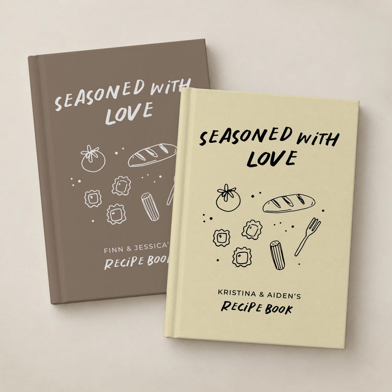 May include: Two hardcover recipe books with a matte finish. The brown book features white text reading SEASONED WITH LOVE and FINN & JESSICA'S RECIPE BOOK. The cream book features black text reading SEASONED WITH LOVE and KRISTINA & AIDEN'S RECIPE BOOK.