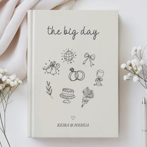 Pu&ograve; includere: Diario di nozze color crema con la scritta "the big day". La copertina presenta disegni a tratto nero di icone nuziali, tra cui anelli, campane e una torta. I nomi "Keira & Joshua" sono stampati sotto.