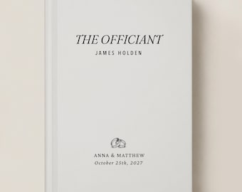 May include: A white hardcover book with black text that reads THE OFFICIANT, JAMES HOLDEN, ANNA & MATTHEW, and October 25th, 2027. A small black and white illustration of two interlocking wedding rings is centered above the names.