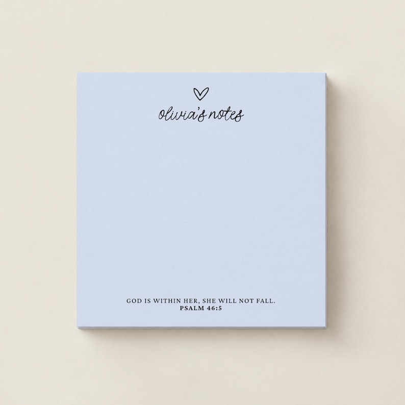 May include: A square light blue notepad featuring a small black heart icon above the cursive text "olivia's notes" at the top. At the bottom, the text "GOD IS WITHIN HER, SHE WILL NOT FALL. PSALM 46:5" is printed in a clean black sans-serif font.