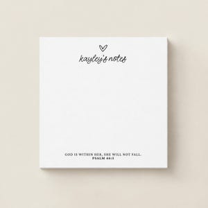 May include: A square white notepad featuring a small hand-drawn heart icon above the text 'kayley's notes' in a cursive script. At the bottom, the text reads 'GOD IS WITHIN HER, SHE WILL NOT FALL. PSALM 46:5' in a clean, black serif font.