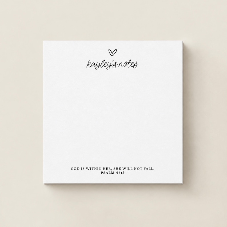 May include: A square white notepad featuring a small hand-drawn heart icon above the text 'kayley's notes' in a cursive script. At the bottom, the text reads 'GOD IS WITHIN HER, SHE WILL NOT FALL. PSALM 46:5' in a clean, black serif font.