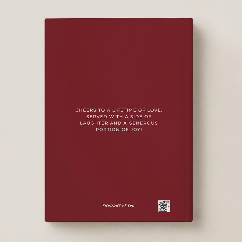 May include: A deep red rectangular book cover featuring centered white text that reads: CHEERS TO A LIFETIME OF LOVE, SERVED WITH A SIDE OF LAUGHTER AND A GENEROUS PORTION OF JOY! The bottom includes the text THOUGHT OF YOU and a small QR code.