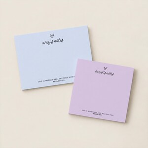 May include: Two rectangular paper notepads in light blue and light purple. The blue pad features the text 'amy's notes' with a heart icon and 'GOD IS WITHIN HER, SHE WILL NOT FALL. PSALM 46:5'. The purple pad says 'sarah's notes' with a heart.