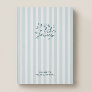 May include: A hardcover prayer journal featuring a light blue and white vertical striped pattern. The front cover displays the dark blue text Love like Jesus with small heart icons and the name Harriet's Prayer Journal at the bottom.