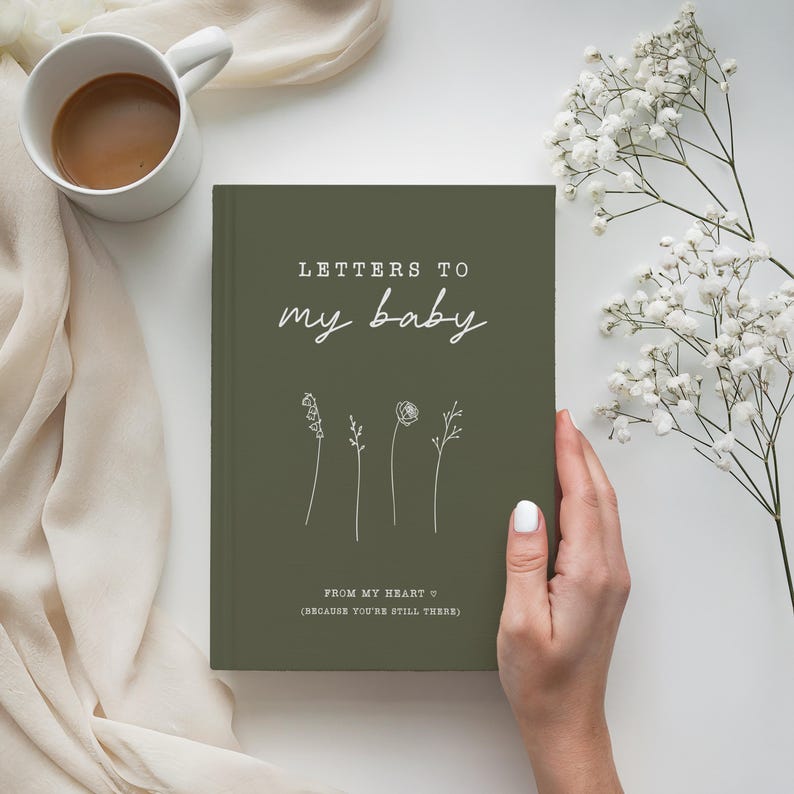 Op de afbeelding: Een groen dagboek met de tekst "Letters to my baby" en "From my heart to (because you're still there)" in wit. Het dagboek heeft een eenvoudig bloemenontwerp.