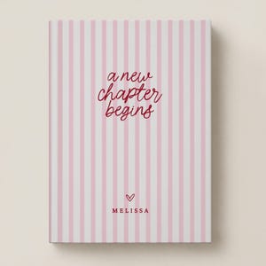 May include: A rectangular notebook featuring a vertical light pink and white striped pattern. The front cover displays the dark red cursive text "a new chapter begins" above a small heart icon and the name "MELISSA" in capital letters.