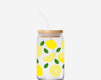 May include: A clear glass drinking cup with a wooden lid and a clear straw. The cup is decorated with yellow lemons and green leaves. The cup is designed to hold cold beverages.