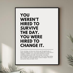 Puede incluir: Impresi&oacute;n enmarcada en negro con el texto "YOU WEREN'T HIRED TO SURVIVE THE DAY. YOU WERE HIRED TO CHANGE IT." El texto est&aacute; en negro sobre un fondo blanco. Tambi&eacute;n hay un p&aacute;rrafo de texto.