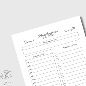 May include: A white planner page with the words "Planificateur Journalier" and "Objectif du jour" at the top. It includes sections for daily planning and a task list, with time slots from 5h to 11h. Decorative hearts and a floral sketch are also present.