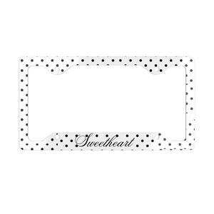 May include: A rectangular license plate frame featuring a white background with a black polka dot pattern. The bottom center of the frame displays the word Sweetheart written in a black cursive script font. The frame includes four mounting holes.