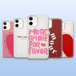 Op de afbeelding: Een verzameling van vijf telefoonhoesjes met verschillende ontwerpen. Eén hoesje heeft de tekst "MORE AMORE POR FAVOR" in roze en oranje. Andere hoesjes hebben het woord "amor" en een hartontwerp.