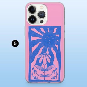 May include: Pink phone case with a blue illustration of a sun, flower, and foliage. The design is centered on the case and features a stylized sun with a face, a daisy-like flower, and decorative leaves and stems.