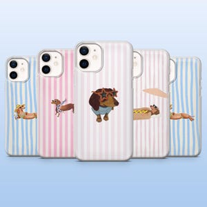 May include: A collection of phone cases with dachshund illustrations. The cases feature vertical stripes in pink, blue, and white. Each case has a different dachshund design, including one wearing sunglasses and a striped shirt.